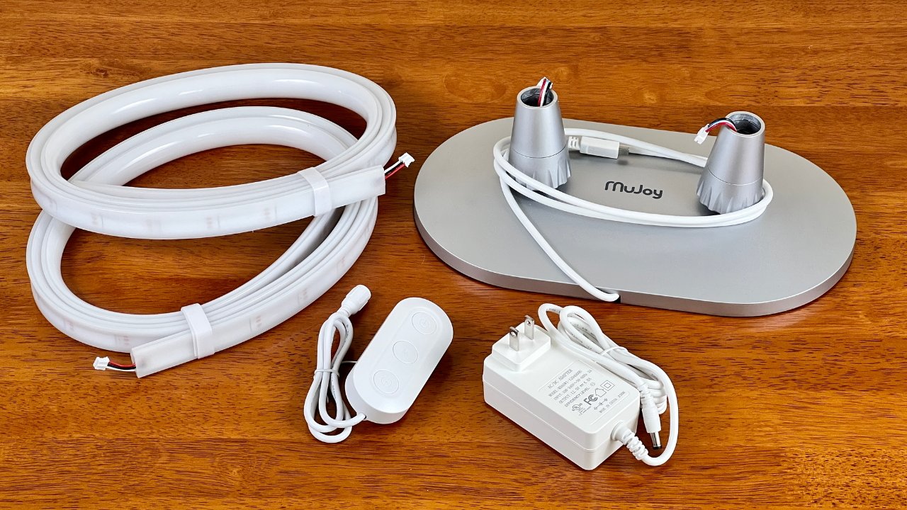 Stojací lampa Mujoy má váženou základnu lampy, napájecí adaptér a dva světelné pásy