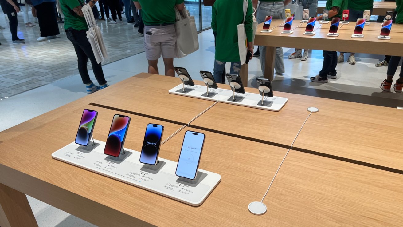 Dřevěné výstavní stoly obklopené zaměstnanci společnosti Apple