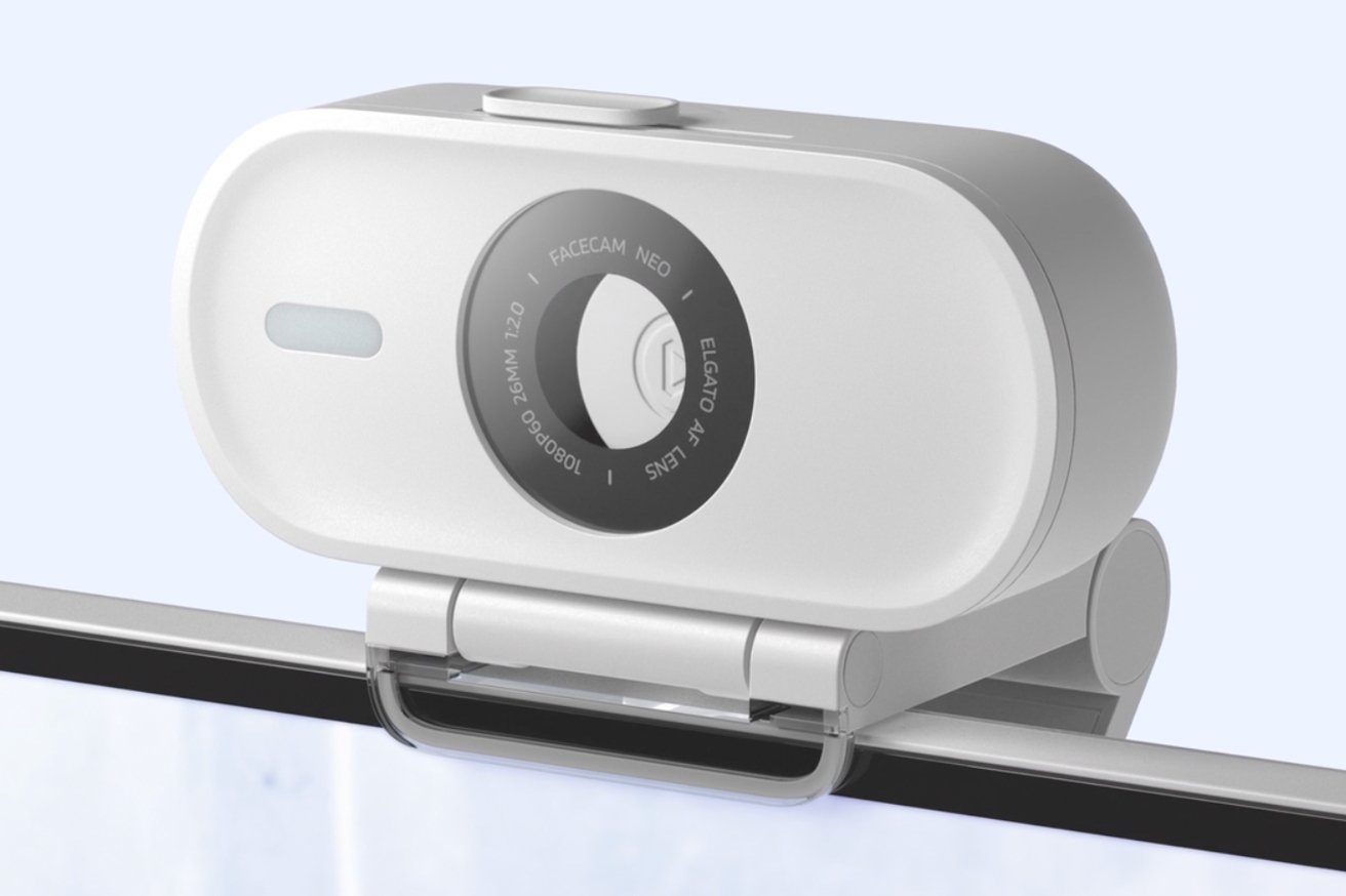 Detailní záběr bílé webové kamery připojené k monitoru, zobrazující ovládací štítky a značku.