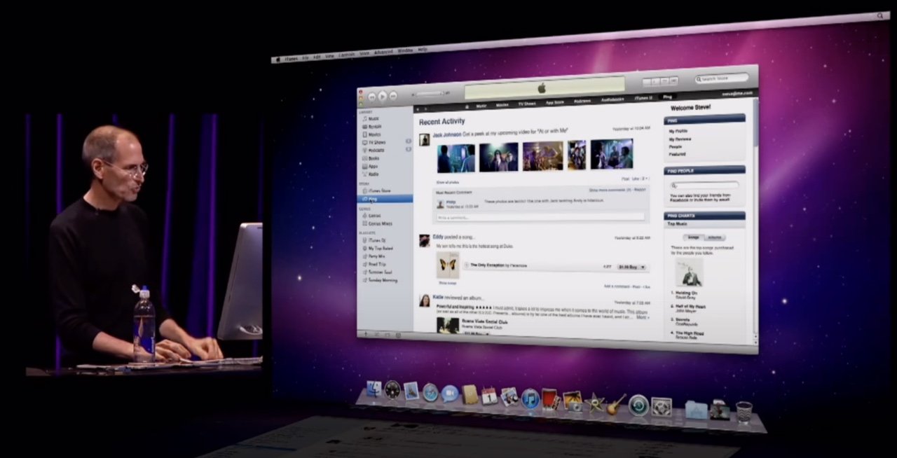 Steve Jobs představuje počítačovou obrazovku zobrazující rozhraní sociálních médií během klíčové prezentace s tmavým pozadím.