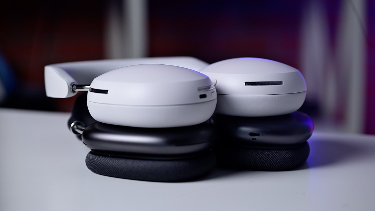 Detailní pohled na moderní bílá sluchátka na uši s polstrovanými náušníky položenými na bílém povrchu.